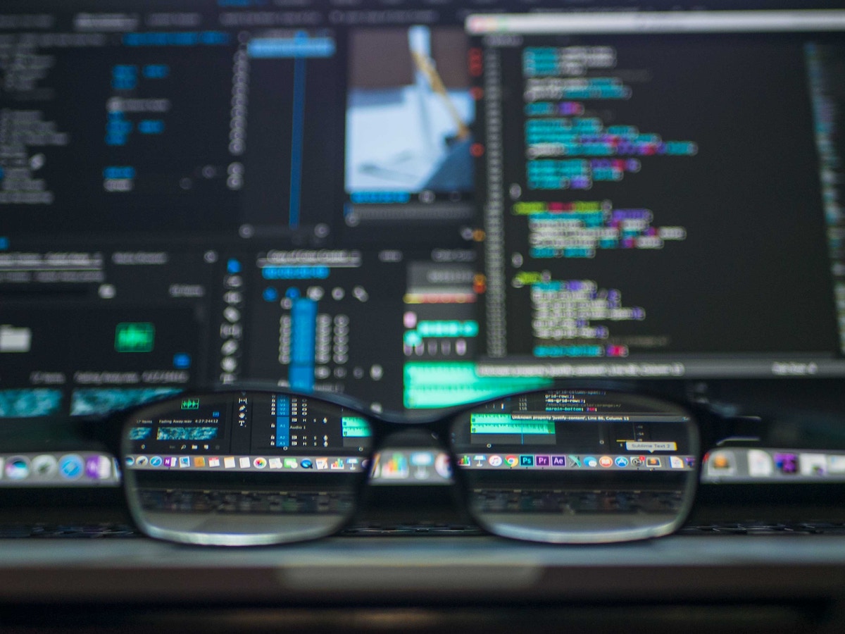 Glasses in front of a screen full of code.